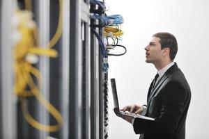 businessman with laptop in network server room photo