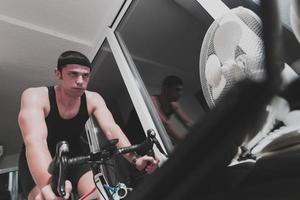 Man cycling on the machine trainer he is exercising in the home at night playing online bike racing game photo