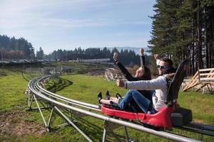 pareja disfruta conduciendo en una montaña rusa alpina foto