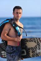 Portrait of a young  kitsurf  man at beach on sunset photo