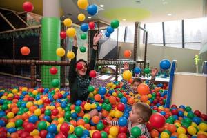 madre joven con sus hijos en una sala de juegos para niños foto