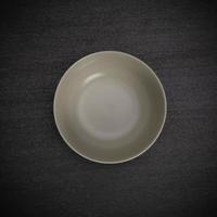 Empty blank white ceramic round bowl on black stone blackground with copy space, Top view of traditional handcrafted kitchenware concept photo