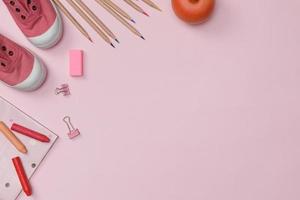 Creative flatlay of education pink table with student books, shoes, colorful crayon, empty space isolated on pink background, Concept of education and back to school photo