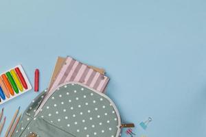 Creative flatlay of education blue table with backpack, student books, colorful crayon, empty space isolated on blue background, Concept of education and back to school photo