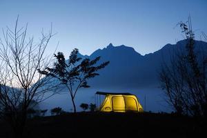 Camp and tent in the night in front of the mountains with cloud in natural park, Tourism concept photo