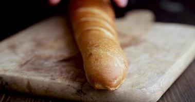 cortar una baguette de trigo crujiente fresca en pedazos durante la cocción foto