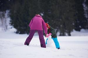 familia feliz construyendo muñeco de nieve foto