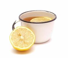 Old metal retro mug with lemon tea and a half of lemon isolated on white background.Useful beverage from autumn cold photo