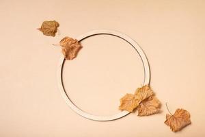 Autumn composition. Wreath made of dried leaves and wooden ring on pastel beige background. Autumn, fall concept. Flat lay, top view, copy space photo