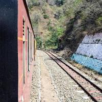 Toy Train moving on mountain slopes, beautiful view, one side mountain, one side valley moving on railway to the hill, among green natural forest. Toy train from Kalka to Shimla in India, Indian Train photo