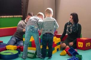 padres jóvenes y niños divirtiéndose en la sala de juegos para niños foto