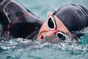 triathlon athlete swimming on lake wearing wetsuit photo