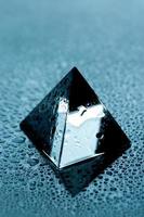 Glass pyramid on wet shiny surface photo