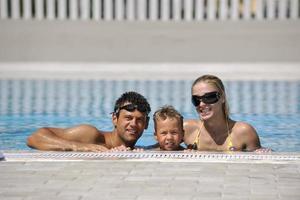 familia joven feliz divertirse en la piscina foto