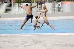 familia joven feliz divertirse en la piscina foto