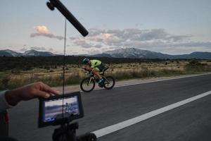 cinematographer taking action shot of triathlon bike athlete photo