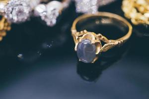 Anillos de zafiro azul de joyería de oro vintage con reflexión sobre fondo negro foto