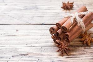 A few cinnamon sticks tied with thread and anise stars on a wooden background. Copy space. Selective focus. photo
