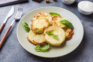 Slices of fried zucchini in batter with garlic and Basil on a plate. photo