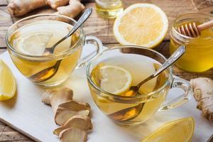 dos tazas de té de hierbas naturales jengibre limón y miel sobre un fondo de madera. foto