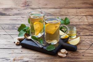 Two cups of natural herbal tea ginger lemon mint and honey on a wooden background. Copy space photo