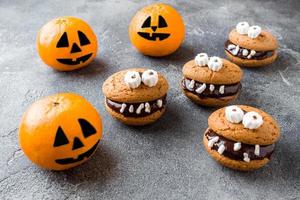 Cookies with chocolate paste in the form of monsters and pumpkin tangerines for Halloween photo