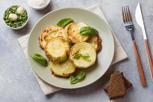 Slices of fried zucchini in batter with garlic and Basil on a plate. photo