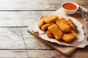 chicken nuggets with tomato sauce on wooden background. Copy space. photo