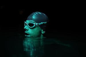 authentic triathlete swimmer having a break during hard training on night neon gel light photo