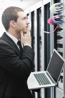 businessman with laptop in network server room photo