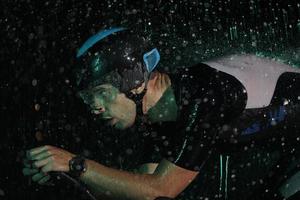 triathlon athlete riding bike  fast on rainy night photo