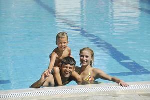 familia joven feliz divertirse en la piscina foto