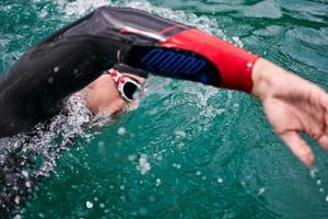 triathlon athlete swimming on lake wearing wetsuit photo