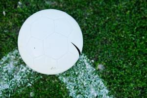 Soccer ball on grass at goal and stadium in background photo