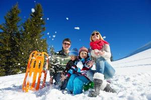 familia divirtiéndose en la nieve fresca en invierno foto