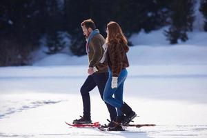 couple having fun and walking in snow shoes photo