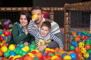 padres e hijos jugando en la piscina con bolas de colores foto