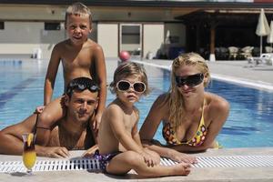 familia joven feliz divertirse en la piscina foto