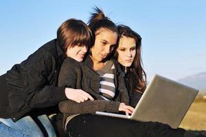 group of teens working on laptop outdoor photo