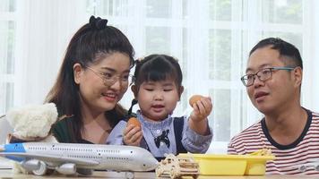 feliz familia asiática en casa de vacaciones padres dando a sus hijos el desayuno huevo carcasa hija