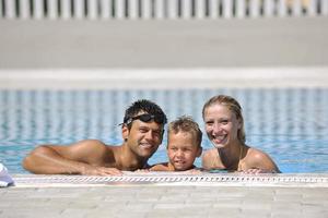 familia joven feliz divertirse en la piscina foto