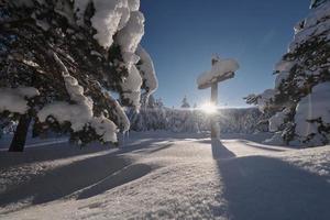 Wooden cross covered with fresh snow at beautiful fresh winter morning photo