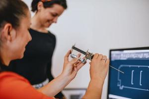 dentro de la industria pesada, un ingeniero industrial de fábrica mide con un calibrador y en una computadora personal diseña un modelo 3d foto