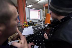 carpenters calculating and programming a cnc wood working machine photo