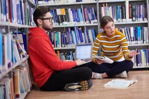 the students uses a notebook, laptop and a school library photo