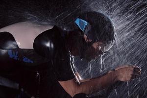 triathlon athlete riding bike  fast on rainy night photo