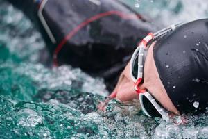 triathlon athlete swimming on lake wearing wetsuit photo