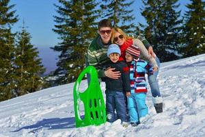 familia divirtiéndose en la nieve fresca en las vacaciones de invierno foto