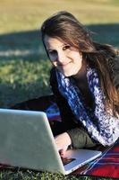Joven adolescente trabaja en una laptop al aire libre foto