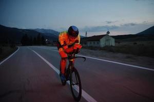 atleta de triatlón montando bicicleta por la noche foto